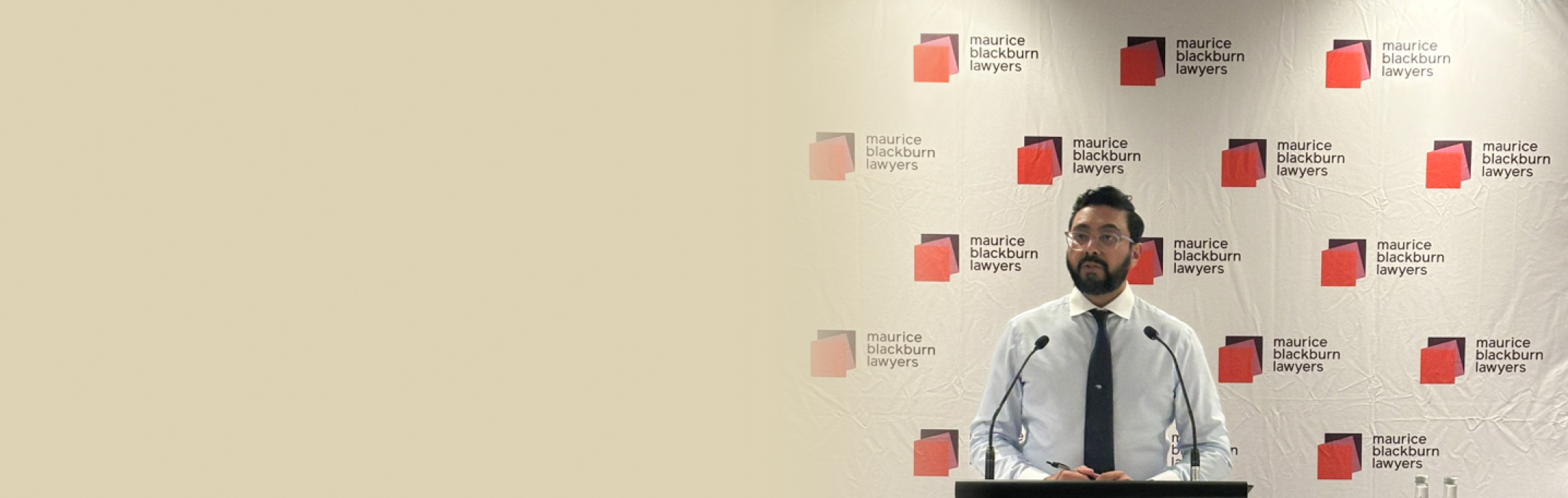 Aftab Malik is speaking at a podium for the appointment inaugural speech with a Maurice Blackburn Lawyers backdrop